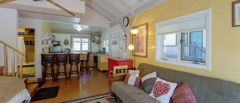 A cozy living room with a sofa, a patterned rug, and a dining area with chairs and a table.
