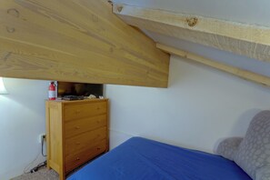 Ein Schlafzimmer mit einem Einzelbett, einem Holzk dresser und einer Decke mit freiliegenden Balken.