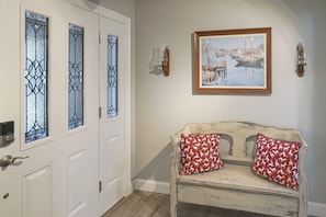 A room with a white door, a bench with red patterned cushions, and a framed painting on the wall. - 13-Acre Vermont Estate w/ Hot Tub & Game Room (West Dover)