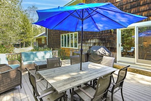 An outdoor patio with a table and chairs, a blue umbrella, and a wooden deck. - 13-Acre Vermont Estate w/ Hot Tub & Game Room (West Dover)