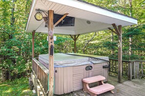 Un bain à remous doté d’une terrasse en bois et d’un banc, entouré d’arbres.