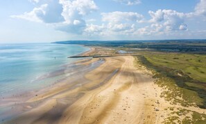 An aerial view of a coastal area with a sandy beach, a curved road, and distant green fields. - Mkrj Comfort Parkdean Camber Sands (Rye)