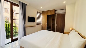 A hotel room with a bed, a TV, a wardrobe, and an air conditioning unit. - Lumen Hotel Phu Quoc (Phuong An Thoi, Dac Khu Phu Quoc)