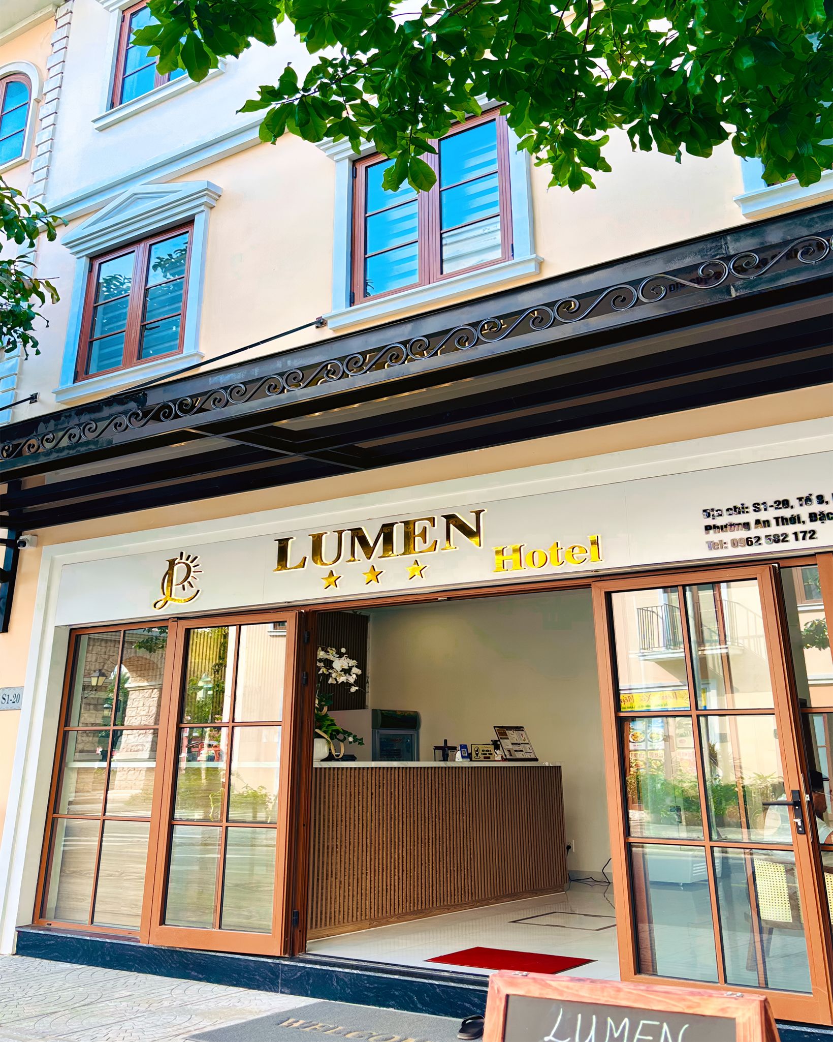 Entrada de un hotel con un cartel que dice 'LUMEN Hotel' y un mostrador de recepción.
