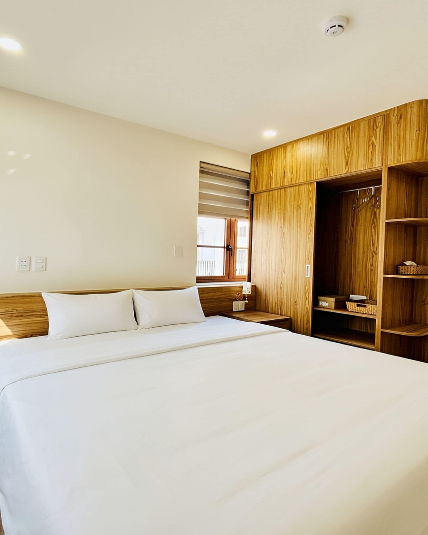 Ein Hotelzimmer mit einem großen Bett, einem Holzschrank und einem Fenster mit Jalousien.
