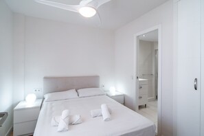 A hotel room with a bed, two bedside tables, a ceiling fan, and a bathroom visible through an open door. - Apartment in Nerja With Beachfront Views (Nerja)