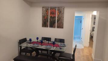A dining area with a table set for four, a bench, and a hallway leading to another room.