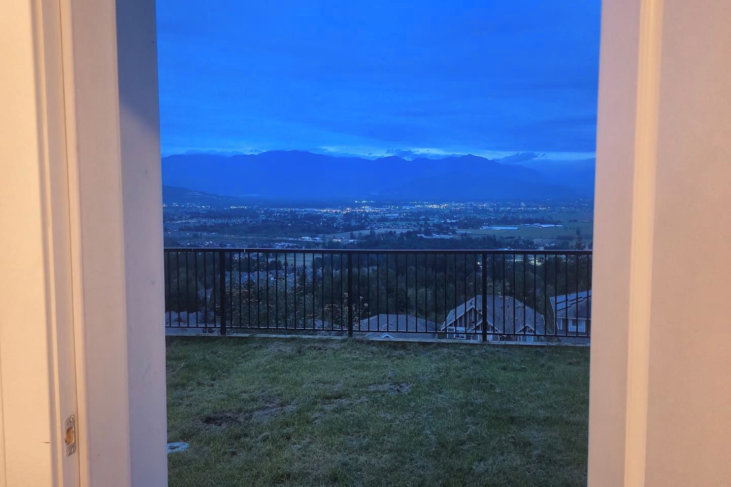 Un balcon doté d’une balustrade en métal, d’où l’on peut admirer un panorama sur la ville et les montagnes lointaines.