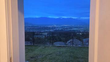 Un balcon doté d’une balustrade en métal, d’où l’on peut admirer un panorama sur la ville et les montagnes lointaines.
