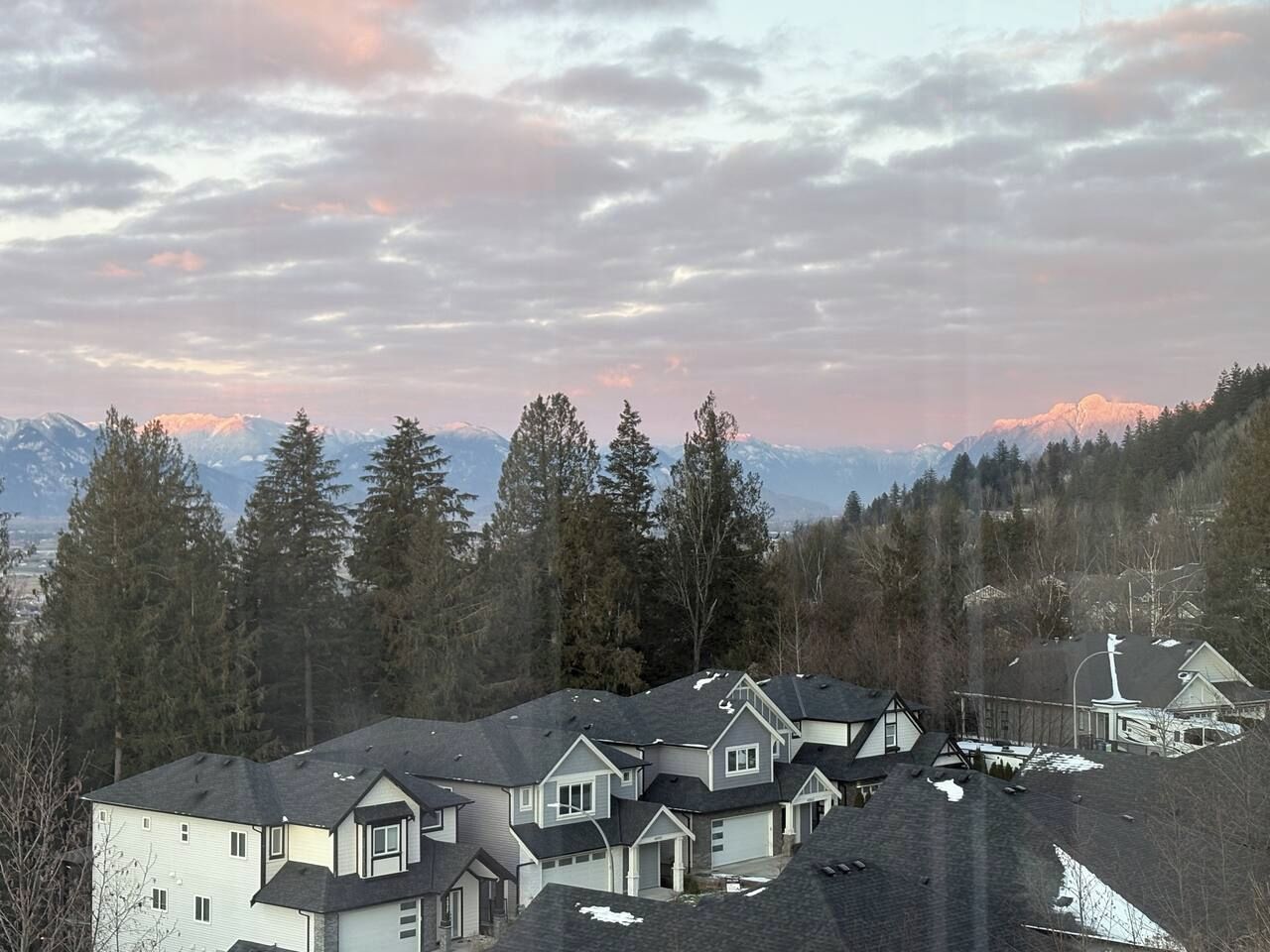 Scenic mountain-view neighborhood framed by trees and glowing sunset skies