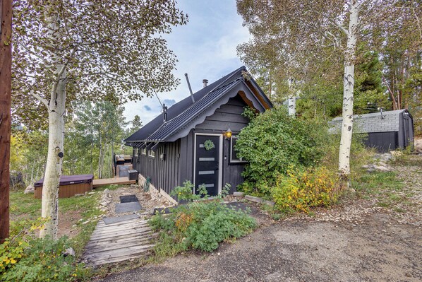 Eine Hütte mit einer Holzdiele, einer kleinen Veranda und einem Garten.