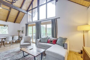 A spacious living room with a high ceiling, a grey sofa set, a coffee table, and a dining area with chairs and a table. - Mtn-View Cabin Escape in Heart of Grand Lake (Grand Lake)