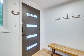 A modern interior with a dark wooden door featuring frosted glass panels, a bench, and a coat rack against a white wall. - Mtn-View Cabin Escape in Heart of Grand Lake (Grand Lake)