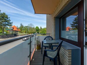 A balcony with a table and chairs, overlooking a road with cars and houses in the background. - 1 "seestern" in Haus Colonia (St. Peter-Ording)
