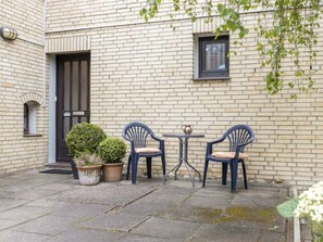 A courtyard with two chairs and a table, a door, and a window. - 1 "seestern" in Haus Colonia (St. Peter-Ording)