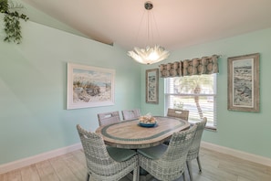 A dining area with a round table, wicker chairs, and a chandelier. - Retreat 7 Mi to Disney! Families w/ Dogs Welcome (Kissimmee)