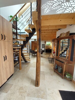 A spacious room with a wooden staircase, a dining area, and a kitchen.