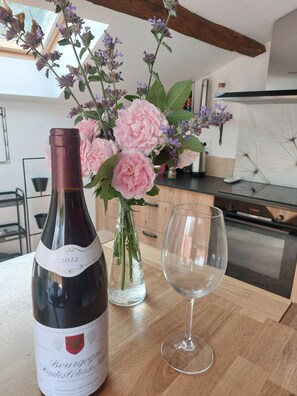 Une bouteille de vin, un verre et un bouquet de fleurs sur une table en bois.