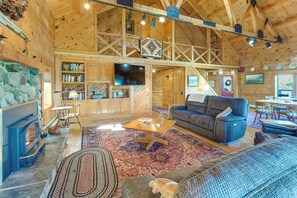 Un interior espacioso de madera con chimenea, estanterías, un televisor de pantalla plana y una zona de estar acogedora.