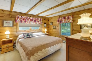 Un'accogliente camera da letto con un letto grande, pareti in legno, una finestra con vista e una lampada sul comodino.