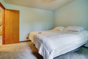 Een slaapkamer met een enkel bed, een deur en een thermostaat aan de muur.