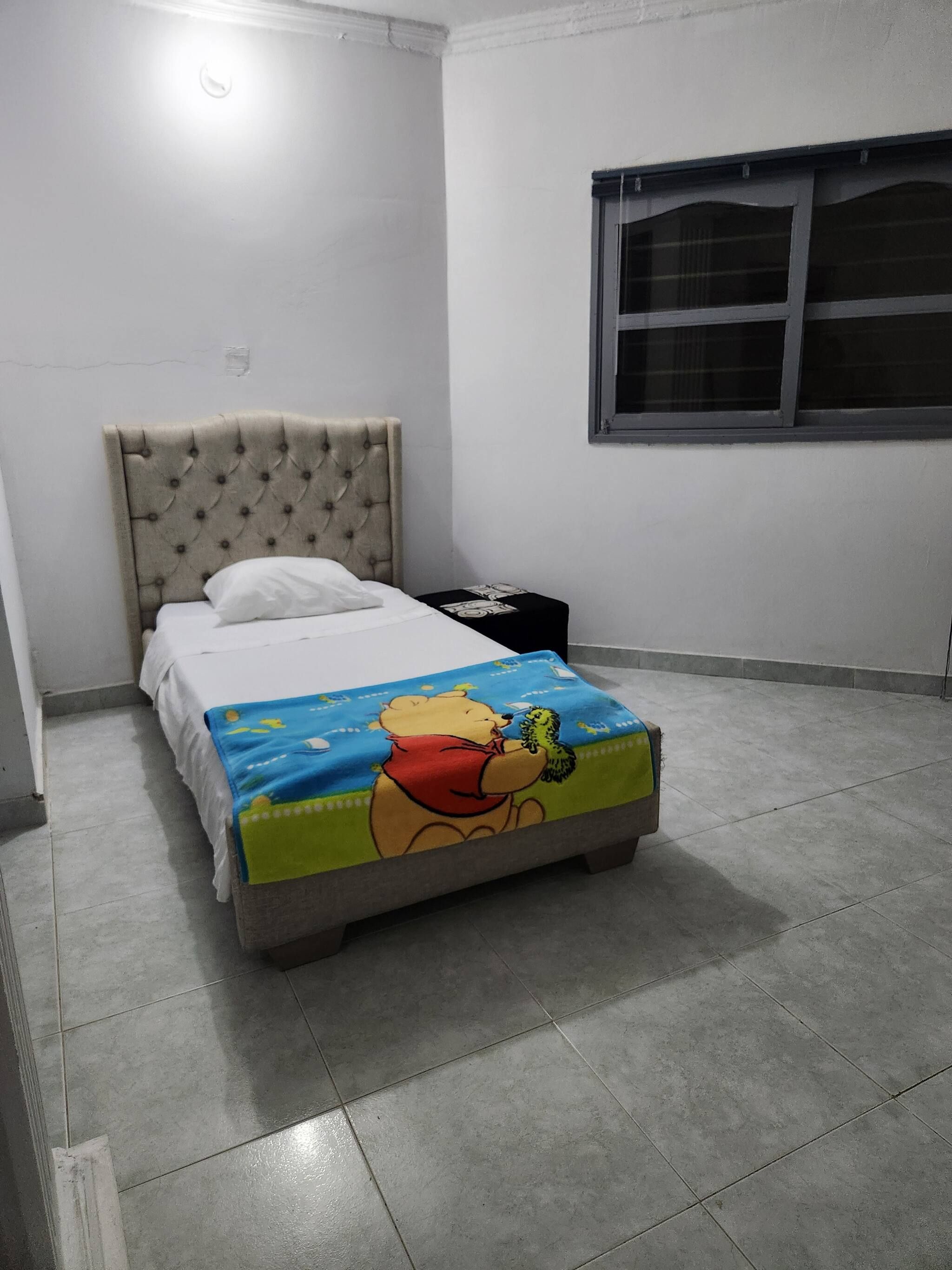 Une chambre à coucher avec un lit, une fenêtre et une table de chevet.