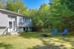 A house with a front porch, a small deck, and a backyard with two Adirondack chairs. - Deck & Private Trails! Hancock Forest Hideaway (Hancock)