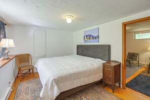 A bedroom with a bed, a chair, a dresser, a lamp, a painting, and a window. - Deck & Private Trails! Hancock Forest Hideaway (Hancock)