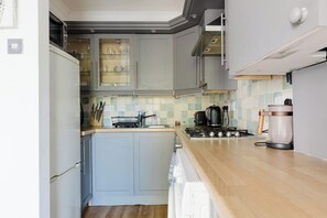 A kitchen with grey cabinets, a wooden countertop, a stove, a kettle, and a coffee maker. - Charming 1BDR Flat by the Canal in Islington (London)