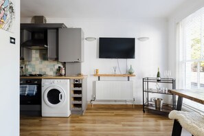 Cocina compacta con lavadora, radiador y televisor montado en la pared.