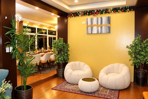 A modern interior with two round seating areas, a dining table with chairs, and a decorative wall piece.