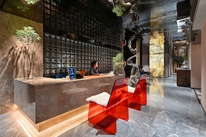 A reception area with a marble counter, a wall of framed photographs, and red chairs. - GOOHUG (Beijing)