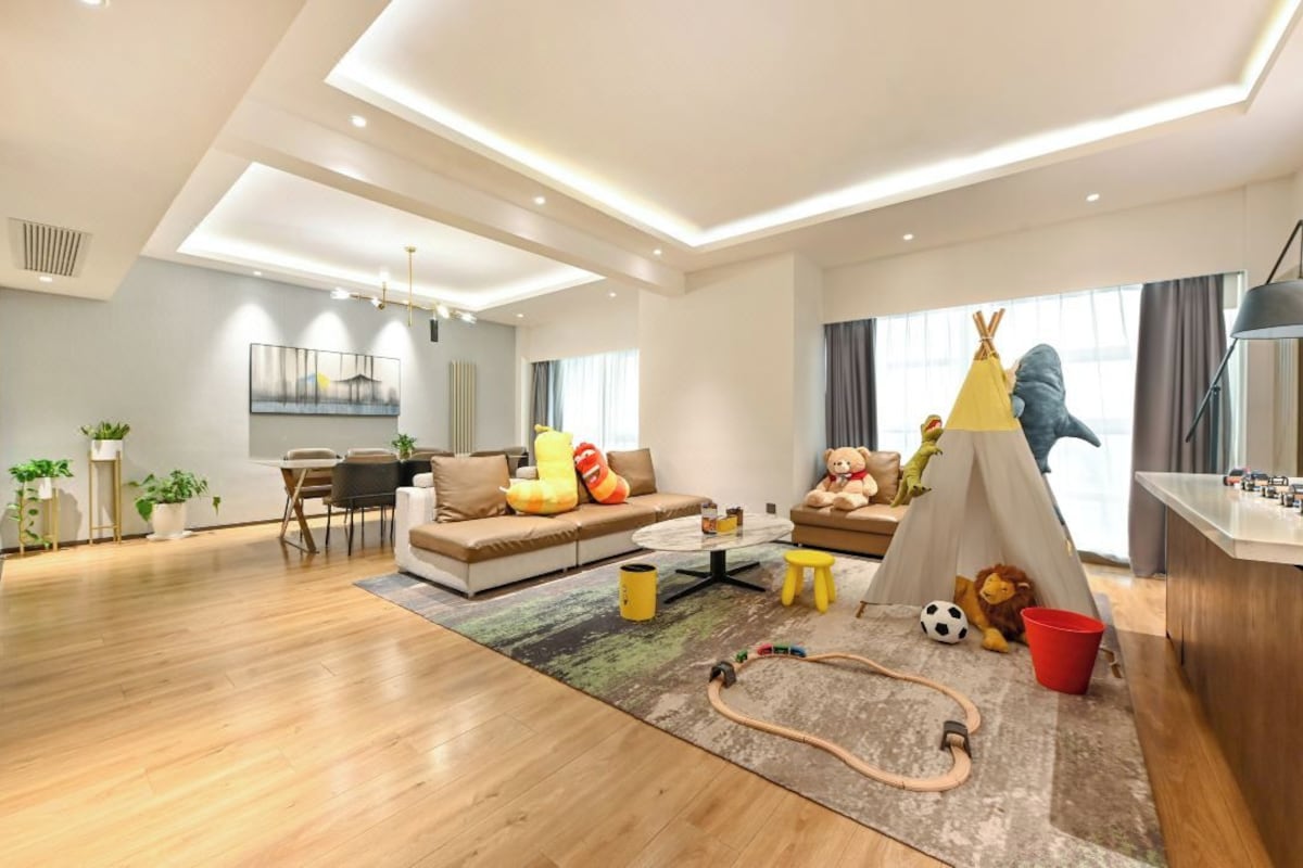 A modern living room with a sofa, coffee table, and a play area with toys and a tent.