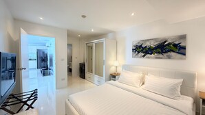 A modern bedroom with a large bed, a walk-in closet, and a bathroom visible through an open door. - B2-Luxurious 80 sqm plus rooftop terrace Retreat Near Karon Beach (Tambon Karon)