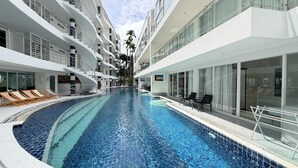 A modern hotel with a central swimming pool, multiple balconies, and outdoor seating areas. - B2-Luxurious 80 sqm plus rooftop terrace Retreat Near Karon Beach (Tambon Karon)