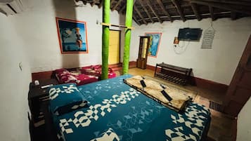 A room with a bed, a bench, a door, and a wall with a painting.