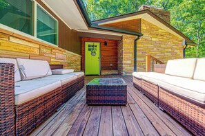 A covered outdoor seating area with wicker furniture and a green door. - Serene Forest Hideaway in Heart of Raleigh (Raleigh)