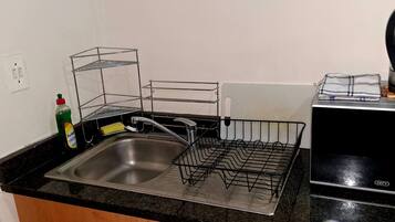 A kitchen with a stainless steel sink, a coffee maker, and a dish rack.