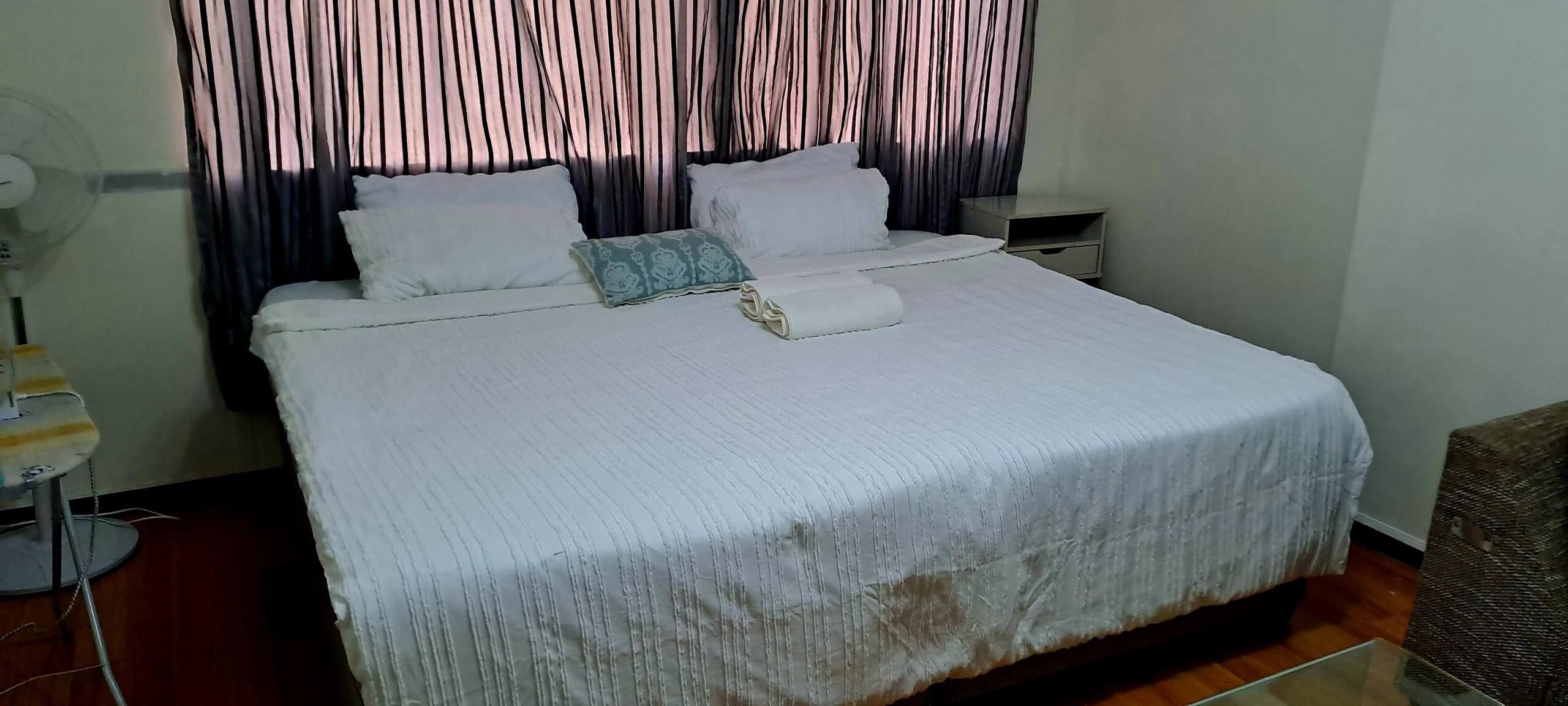 A standard hotel room with a bed, a nightstand, a lamp, and a curtain.