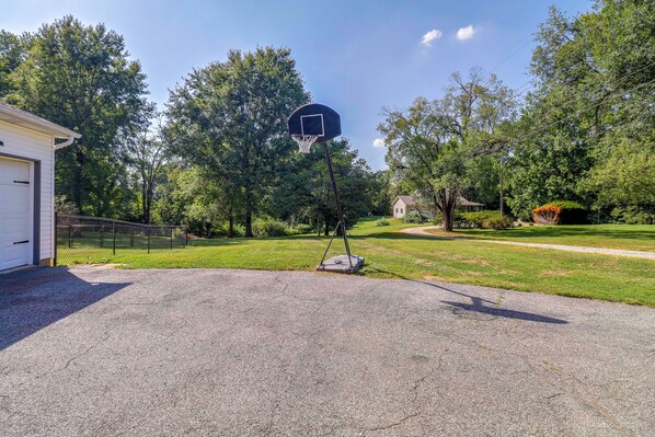 Ein Einfahrt mit Basketballkorb, Garage und gepflegtem Rasen.