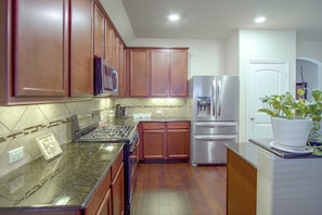 A kitchen with wooden cabinets, a stainless steel refrigerator, a microwave, and a gas stove. - Lewisville Lake Escape, 4 Mi to Boat Ramp (Little Elm)