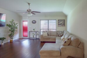 A living room with a ceiling fan, a sofa, a coffee table, and a door with red blinds. - Lewisville Lake Escape, 4 Mi to Boat Ramp (Little Elm)