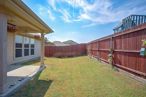 A residential backyard with a wooden fence, a house with a covered porch, and a clear sky. - Lewisville Lake Escape, 4 Mi to Boat Ramp (Little Elm)
