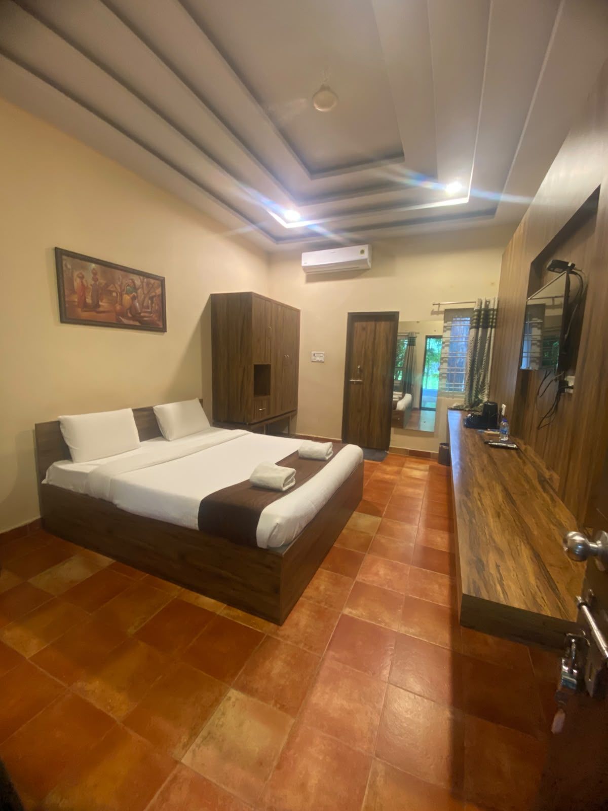 A bedroom with a large bed, wooden wardrobe, and a bathroom visible through an open door.