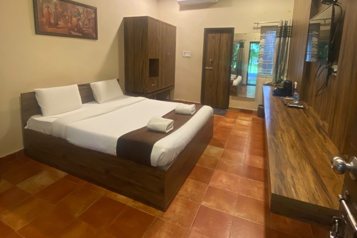 A bedroom with a large bed, wooden wardrobe, and a bathroom visible through an open door.