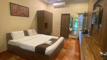 A bedroom with a large bed, wooden wardrobe, and a bathroom visible through an open door.