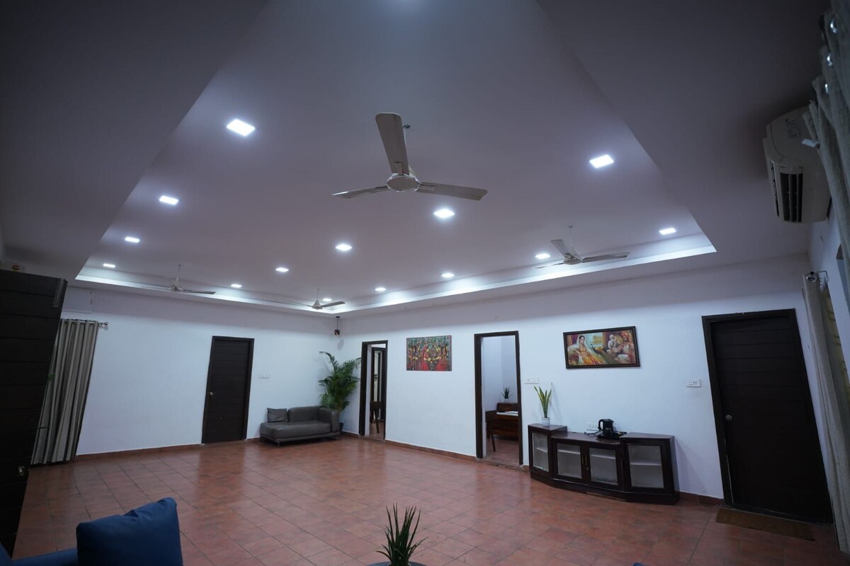 A spacious room with a ceiling fan, recessed lighting, a sofa, a coffee table, and a potted plant.