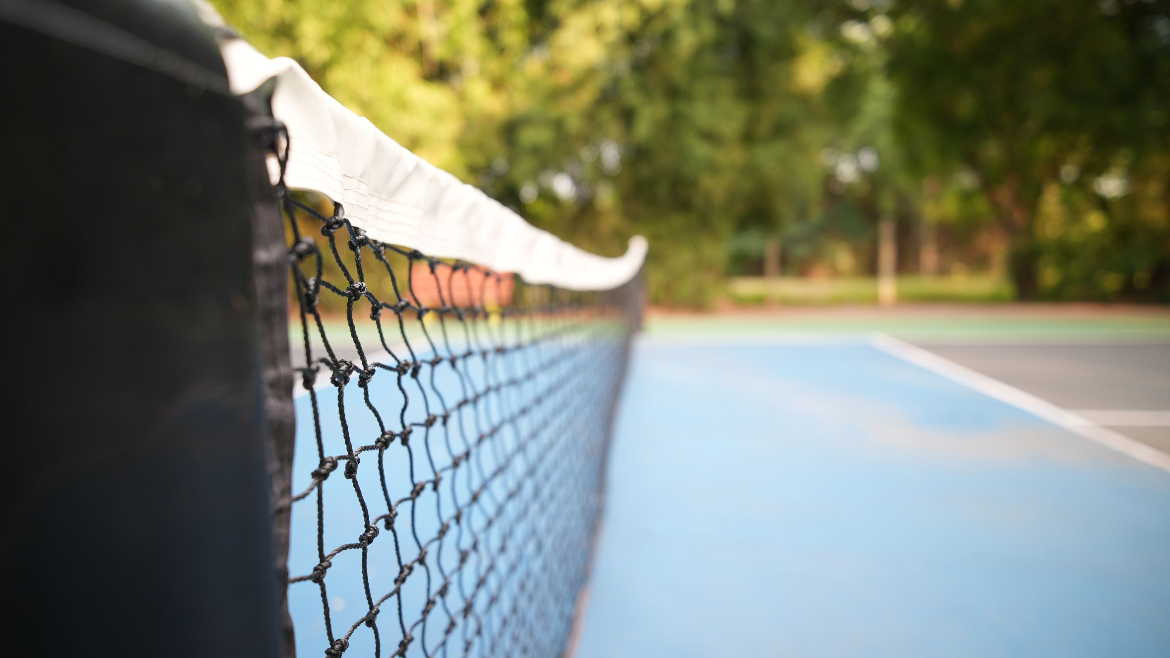 A tennis court with a net in the foreground.