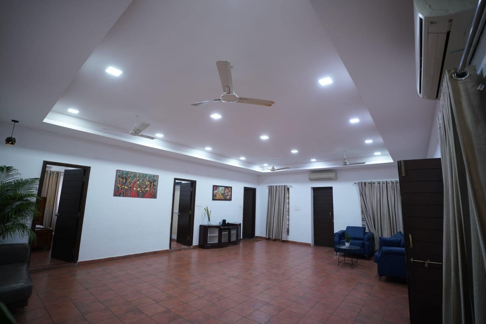 A spacious room with a high ceiling, recessed lighting, a ceiling fan, and a tiled floor.
