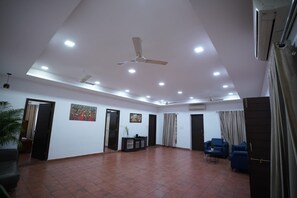 A spacious room with a high ceiling, recessed lighting, a ceiling fan, and a tiled floor.